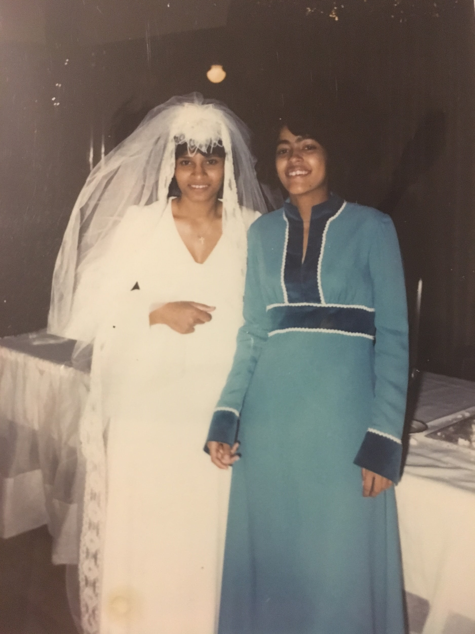 A woman in a bridal dress and veil with a woman in a blue dress.