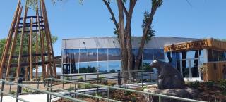 Front of the Ute Indian Museum, with a large teepee structure, tall tree, and a bear sculpture. A ramp leads to the main entrance. 