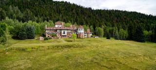 Looking upslope, across the front lawn, towards Redstone Castle. Trees cover the hillside slope behind the building. 