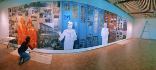 Artist in the process of painting a large indoor mural.