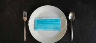 A plate with a mask on it and a fork and spoon