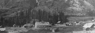 Black and white photo of Gothic Hotel in Gothic Colorado, shadowed by a large mountain. 
