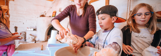 2 children mix tortilla dough with their hands as a teacher assists.
