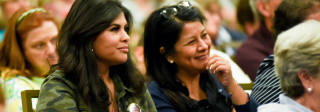 A group of women sit and listen to a presenter