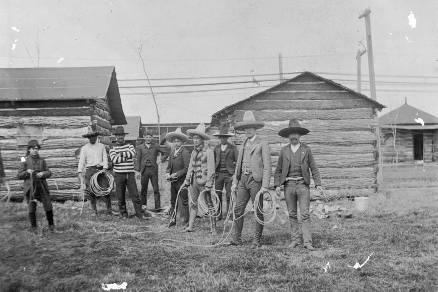 Vaqueros featured in Buffalo Bill's Wild West Show, posing with ropes, traditional outfits, and in front of cabins.