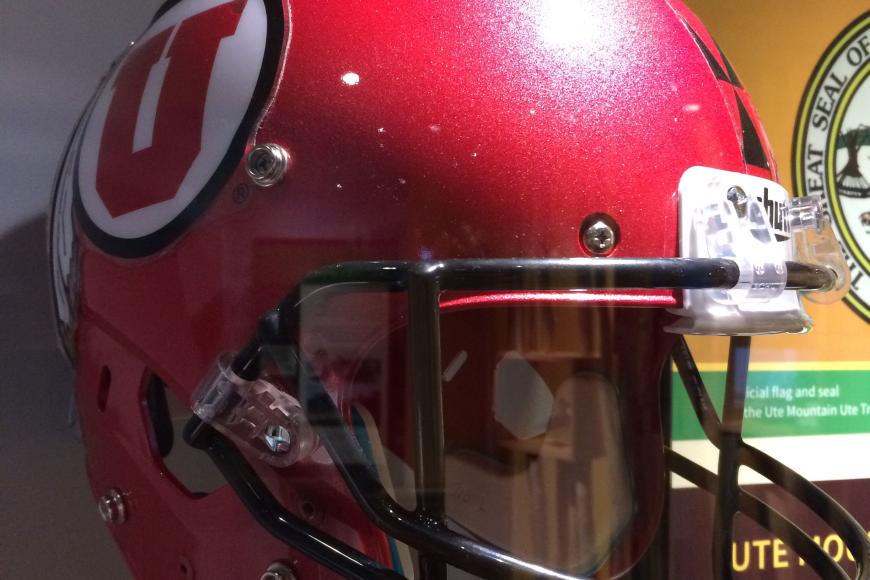 A red football helmet in a display case. The helmet has a large U on the side.