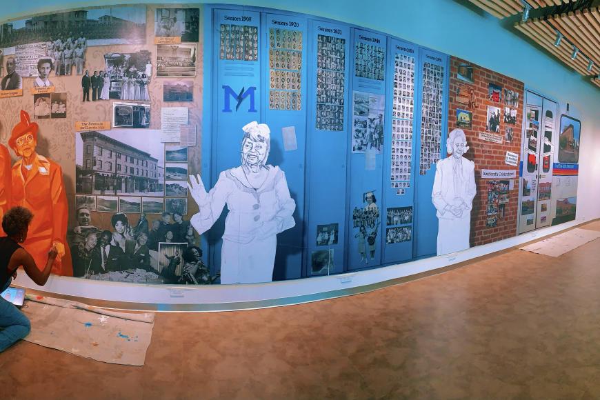 Artist in the process of painting a large indoor mural.