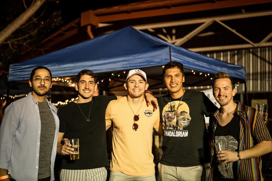 A group of young people pose in front of an external venue at the Bruja Brewfest beer festival at El Pueblo History Museum.