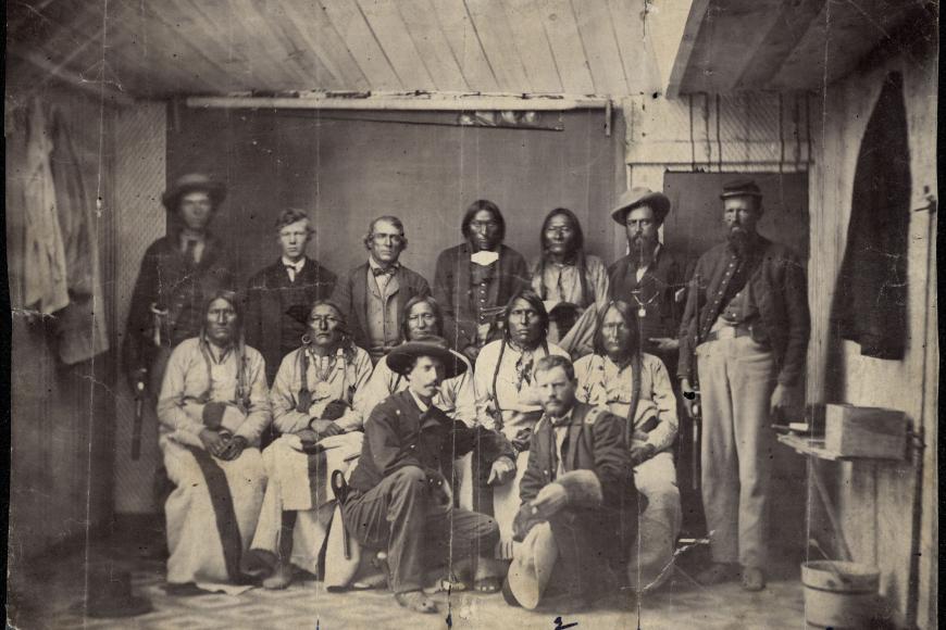 A black and white photo of a group of men posing. Some of the men are Native Americans, some are Anglo-American soldiers.