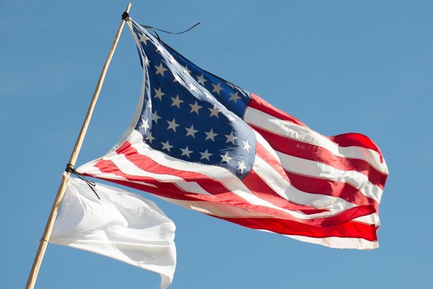 American flag flying alongside a white flag of peace.