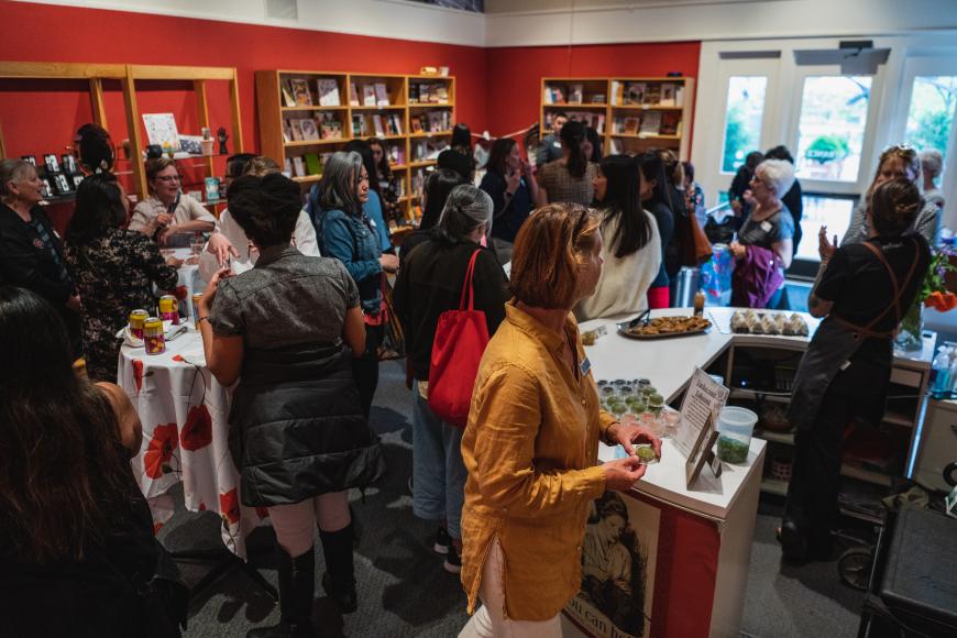 Interior of CCWH visitor center where a large group of guests are conversing. They are around tableclothed tables and counters filled with canapes.