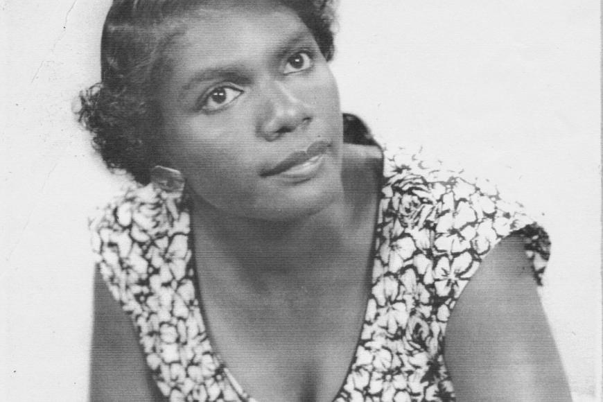 Portrait of Ada Belle Evans wearing a floral dress and leaning towards the camera.