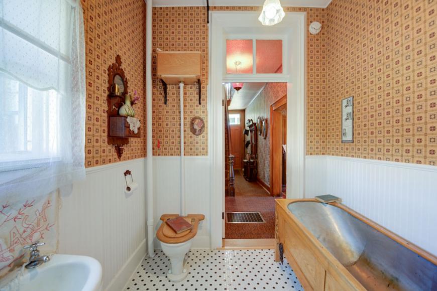 A Victorian style bathroom with a metal tub incased in wood.