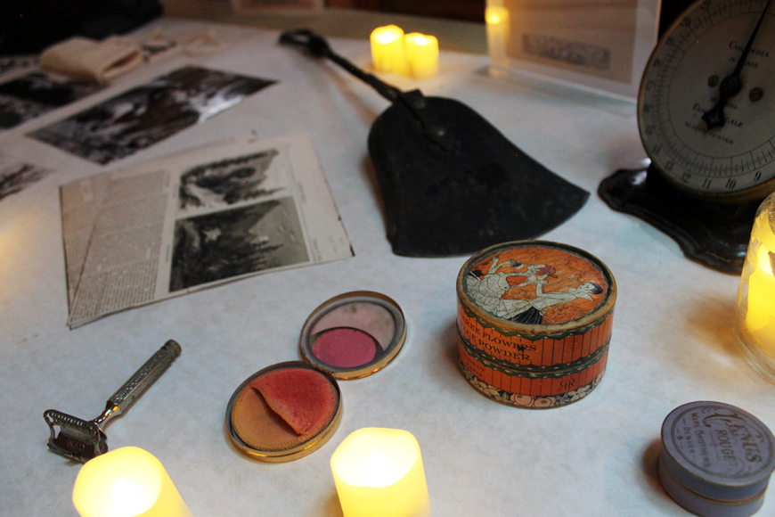 Table full of mortuary and funerary items such as makeup, razors, rouge, and weights.
