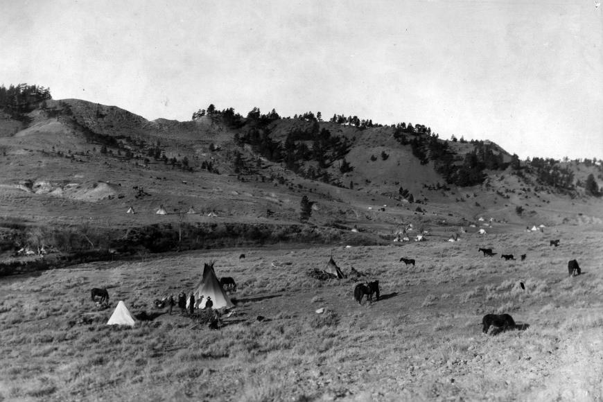 Ute Camp Near Wyoming-Montana Border dotted with tepees and Native American people.