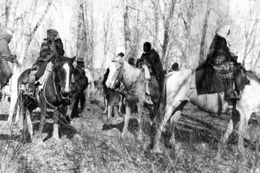 3 Ute women wrapped in blankets and scarves sit on horseback preparing to travel.