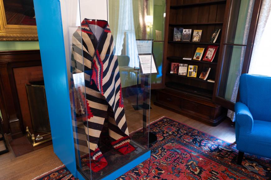A woven indigenous blanket around a mannequin in a glass case at the Ms Destiny exhibition