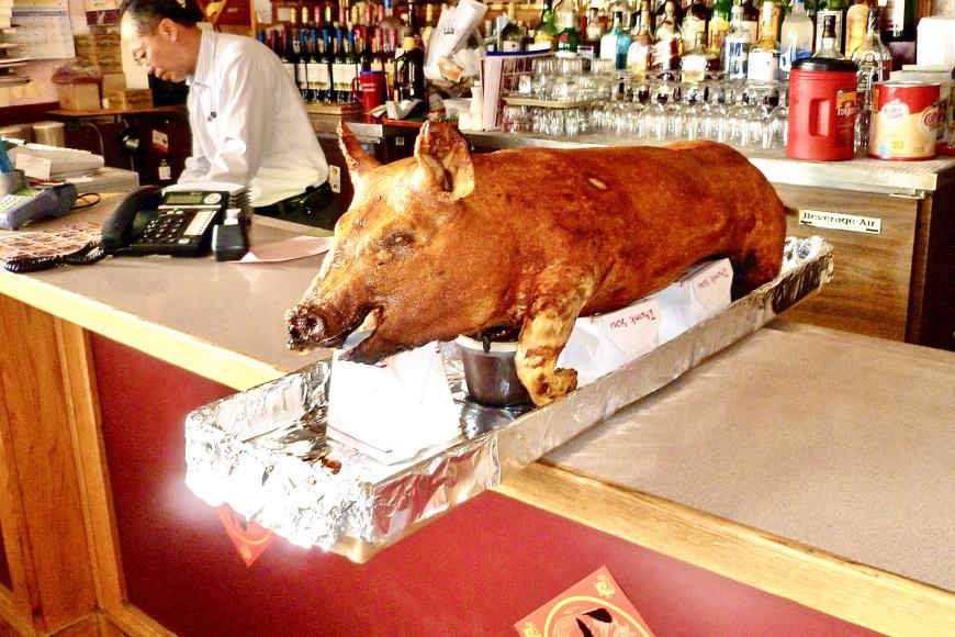Close up of a whole roast pig on a restaurant counter.