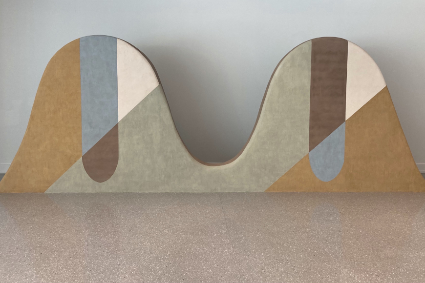Abstract art sculpture showing 2 rounded peaks with brown and grey shapes decorating it.