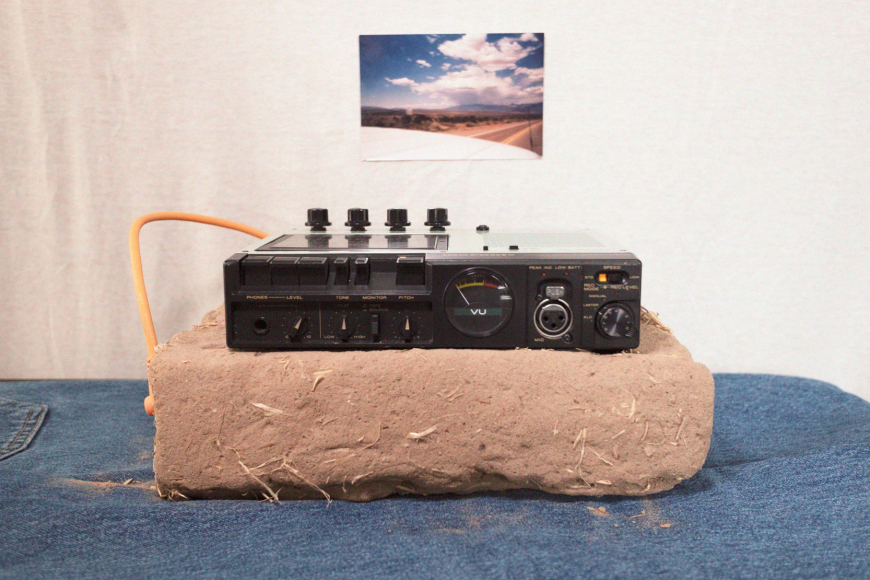 artwork by Santino Gonzales of a large slab of mud and radio equipment plugged into it.