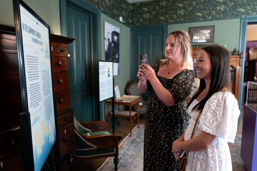 Woman taking picture of exhibit with another visitor