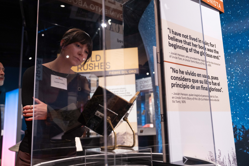 A woman reads a book on display at Moments that Made US