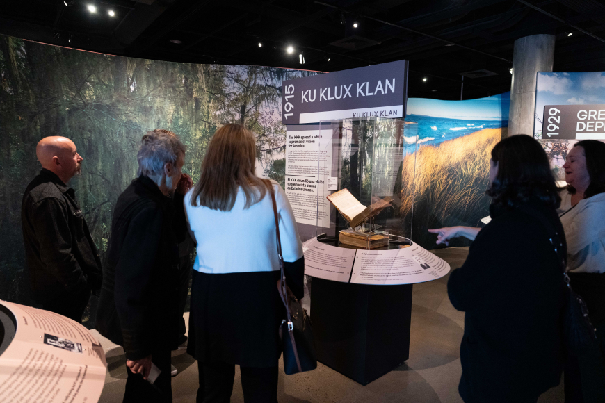 A group of guests read and discuss the display describing the Ku Klux Klan in the exhibition.
