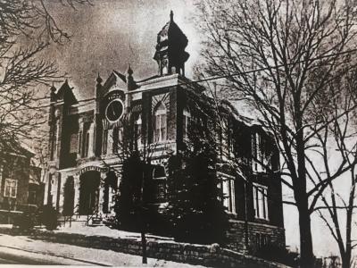 Photo of Temple Aaron, long before the completion of a preservation project. This historic black and white photo shows the brick building sitting on a hill, the slope of the hill visible in the image. There is a front porch made of brick, and a large round window in the building directly above the door. There are gothic style arched windows and decorative finials along the roof of the building.