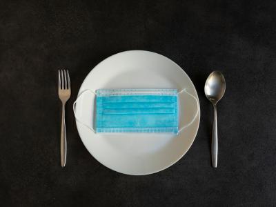 A plate with a mask on it and a fork and spoon