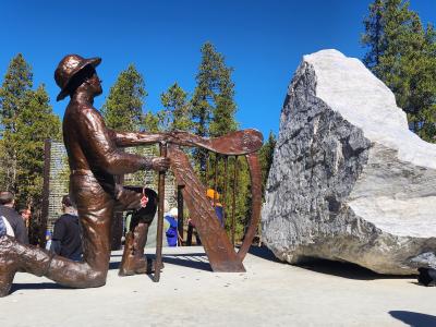 A perspective of the centerpiece of the Leadville Miners' Memorial, which depicts a man with a pick, kneeling at an Irish harp.