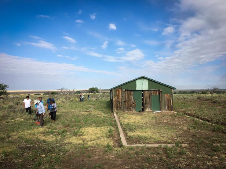 Photo of Students of the Amache Field School walking around the foundations of former buildings which sat in the midst of great arid plains.