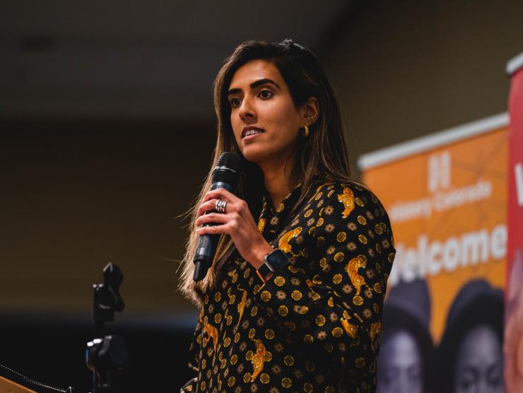 Sarah Aziz speaking at History Colorado Center in front of two banners