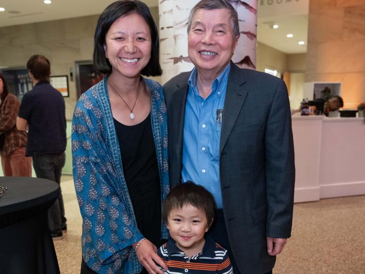 A family of two parents and a young man smile in the HCC atrium.