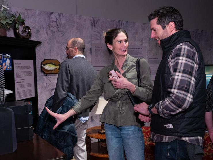 2 guests motion to a display case in the 90s exhibition.