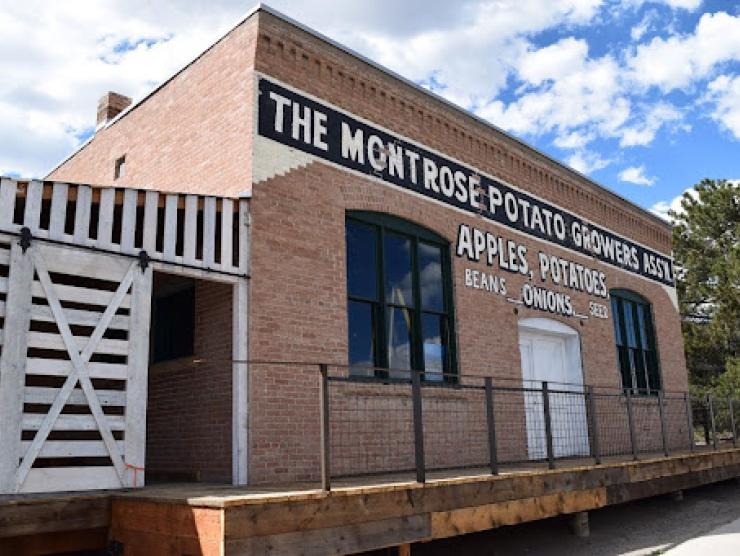 Exterior of a one story brick building that reads The Montrose Potato Growers Assc. Apples, POtatoes, Beans, Onions, seed.