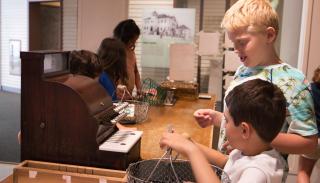 Children playing with an old cash register in a museum.
