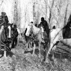 3 Ute women wrapped in blankets and scarves sit on horseback preparing to travel.