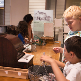 Children playing with an old cash register in a museum.