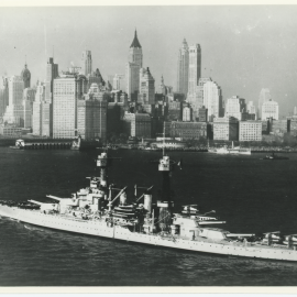 USS Colorado floating in water with New York City skyline in distance.