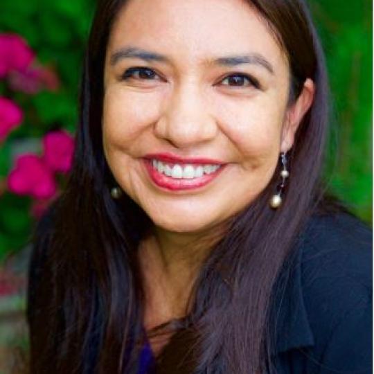 Photo of Kathryn Redhorse. She has long, straight, dark hair and is wearing a navy blue jacket and a blue blouse. She is smiling.